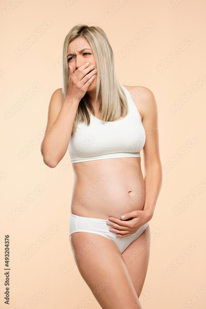 Fototapeta premium Young pregnent woman in lingerie disgusted suffering with nausea