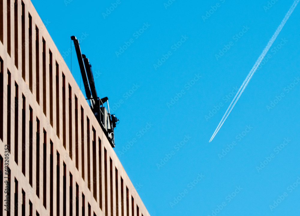 Airplane trail forming a V shape with modern office building and a crane. Airplane trail forming a V shape with modern office building and a crane.