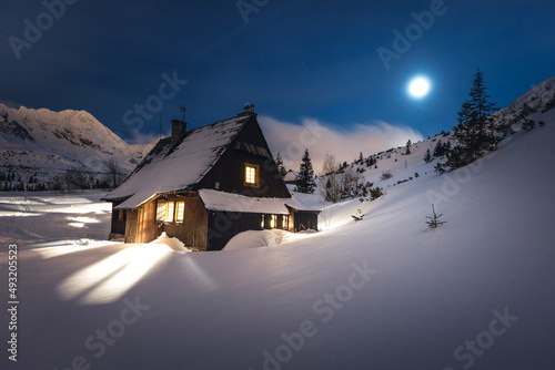 Fototapeta Naklejka Na Ścianę i Meble -  Mountain chalet in the Tatras during the blue hour. Winter mountain landscape with a view of the mountain ridges.