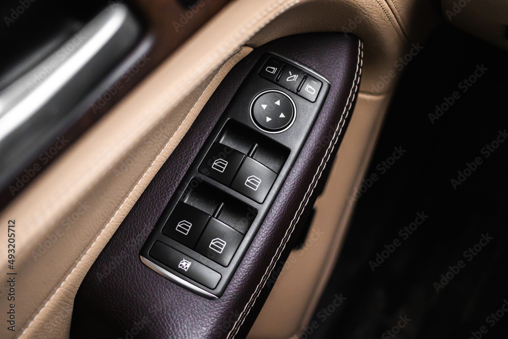 Car door and windows open close buttons. Luxury car interior with brown leather background