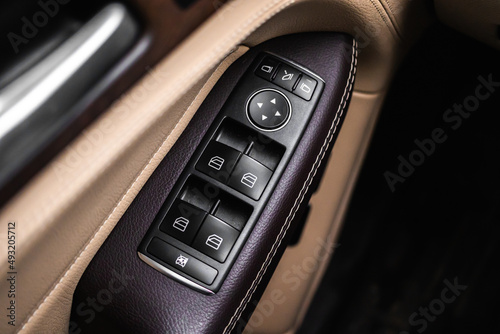 Car door and windows open close buttons. Luxury car interior with brown leather background © FellowNeko