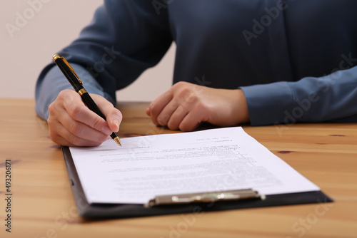 Businesswoman signing contract at wooden table, closeup of hands