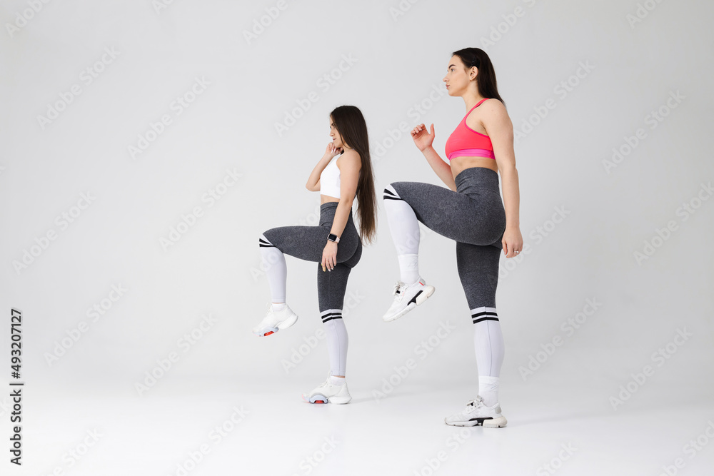 Obraz premium Two young fitness women exercising in the studio