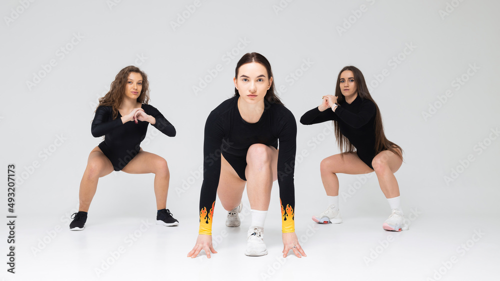 Obraz premium Three girls dancing in the studio on a white background