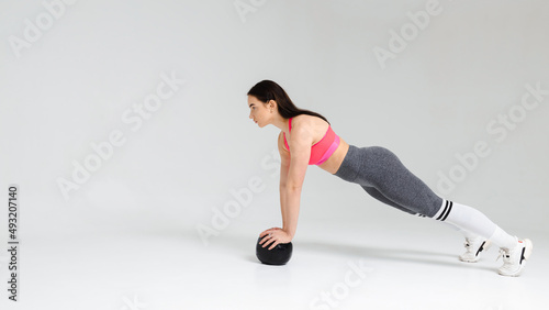 Athletic woman doing exercise with medicine ball on a white background in the studio
