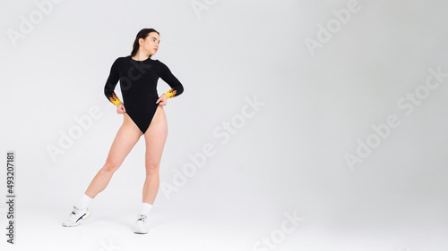 Attractive girl dancer in a black bodysuit posing in the studio on a white background