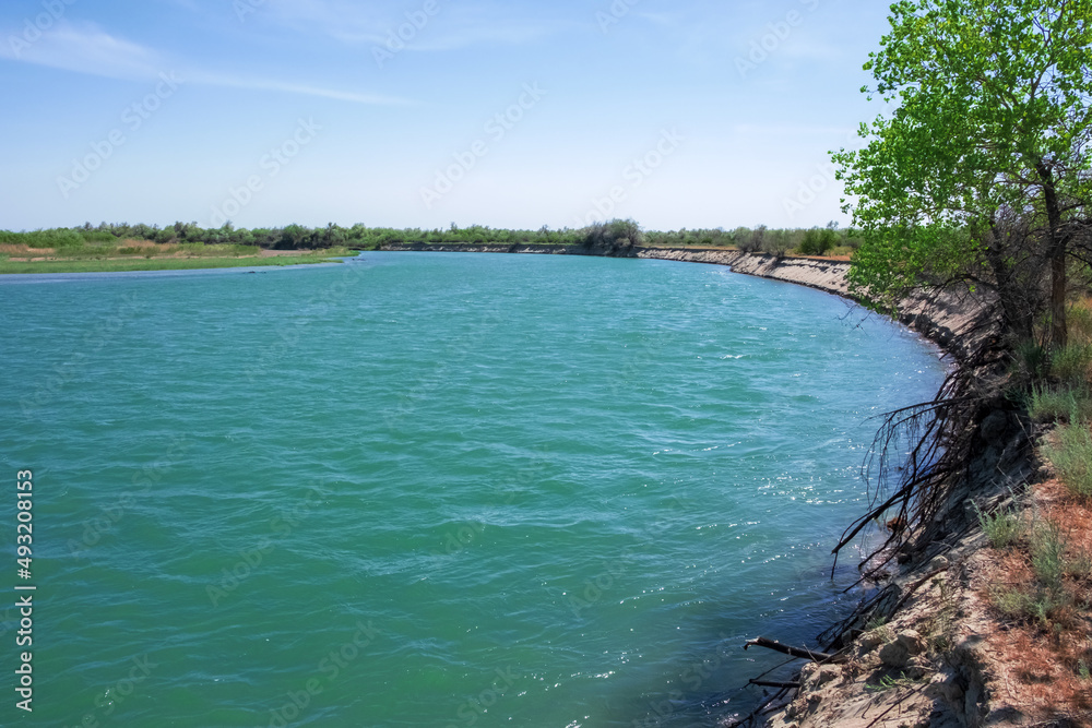 Ili river in spring time. Beautiful river with blue water and sky. Wild nature landscape background. Ili river in spring time. Beautiful river with blue water and sky. Wild nature landscape background.
