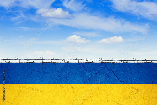 Muro con i colori della bandiera ucraina recintato da filo spinato. photo
