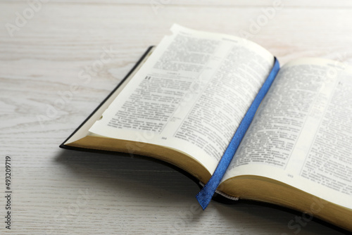 Fototapet Open Bible on white wooden table. Christian religious book