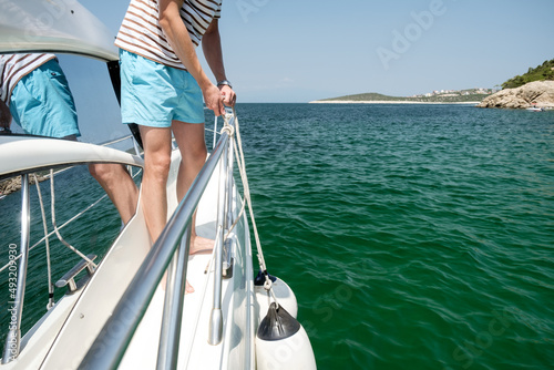 Young man on yacht desk making marine knot photo