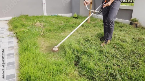 Man cutting grass in front of house. photo