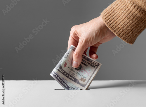 charity, financial support and saving concept - close up of hand putting money into donation box photo