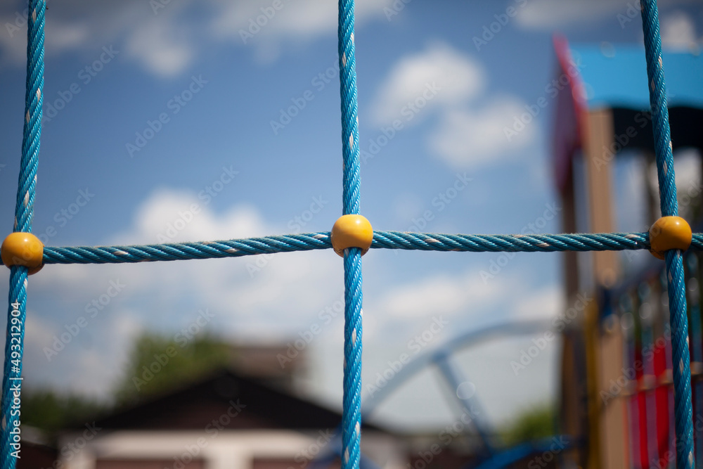 Children's playground in detail. Rope ladder in children's area. Blue ropes connected in net. Place to play for children in summer. Children's playground in detail. Rope ladder in children's area. Blue ropes connected in net. Place to play for children in summer.