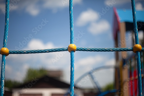 Children's playground in detail. Rope ladder in children's area. Blue ropes connected in net. Place to play for children in summer.