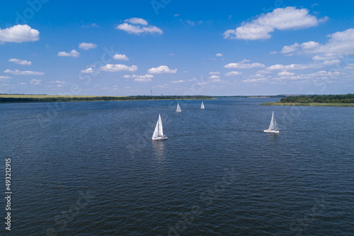 View from the air on the steppe river on a bright sunny day, on the river sailing boats. Sailing sports on the river.