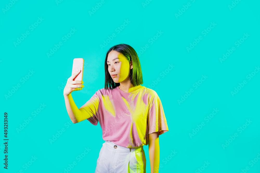 Young asiatic woman isolated using smartphone taking selfie