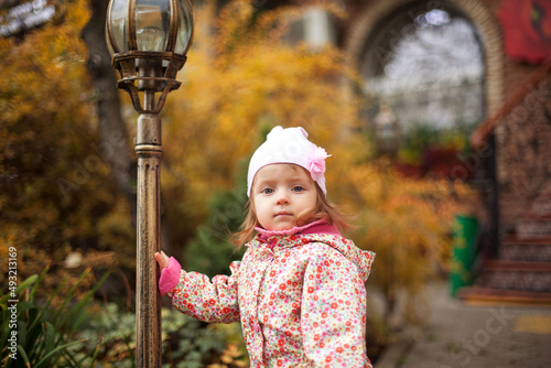 Little beautiful girl portrait in autumn street. Happy smart small girl in autumn park photo