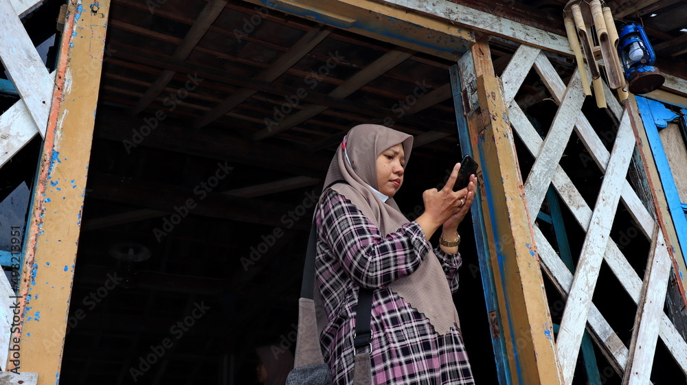 a woman wearing a hijab while using her phone to send news a woman wearing a hijab while using her phone to send news