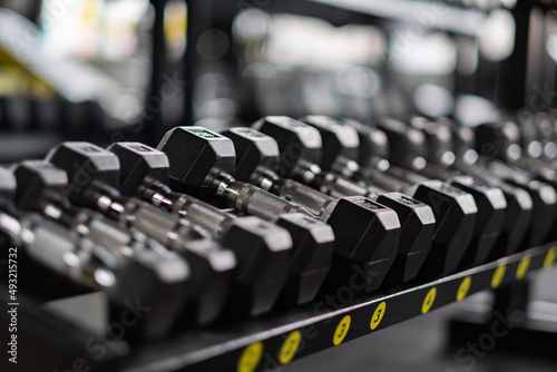Dumbbells lie in a row in the gym. Blurred background . High quality photo