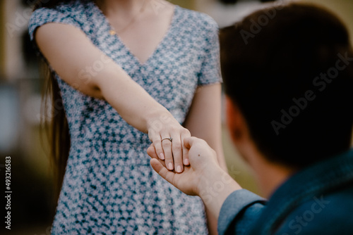 Close up of holding hands in woods with engagement ring