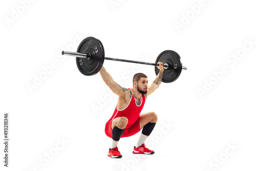 Portrait of man in red sportswear exercising with a weight isolated on white background. Sport, weightlifting, power, achievements concept
