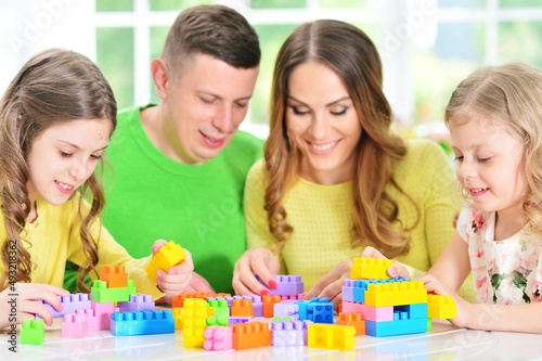 Girl with mother and father playing with colorful plastic blocks