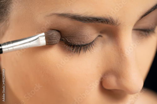 woman applying eye shadow with a brush photo