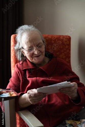 Pensionner lady looking at pictures in her couch at home photo