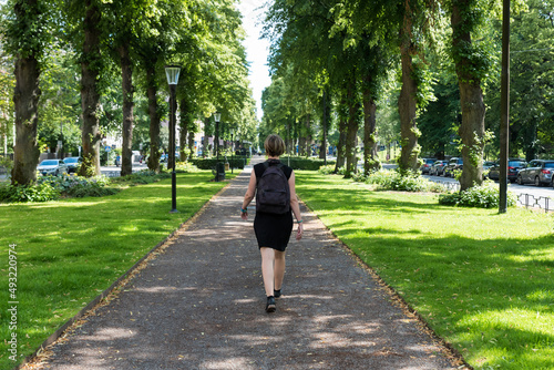 Photography Attractive woman in black dress walking in a green city park