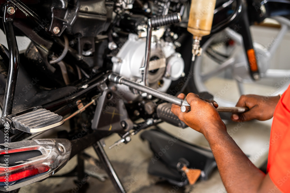 shoulder shot of focus on hands, motorbike mechanic fixing or reparing engine at garage - concept of maintenance service and occupation. shoulder shot of focus on hands, motorbike mechanic fixing or reparing engine at garage - concept of maintenance service and occupation.