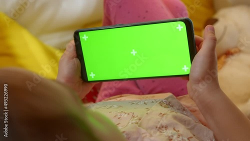 Green screen on a smartphone in the hands of a preschool girl.