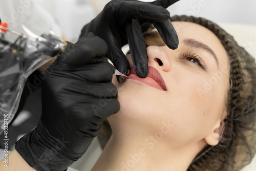 Close-up of the permanent makeup procedure. Lip makeup in the cosmetologist s salon.