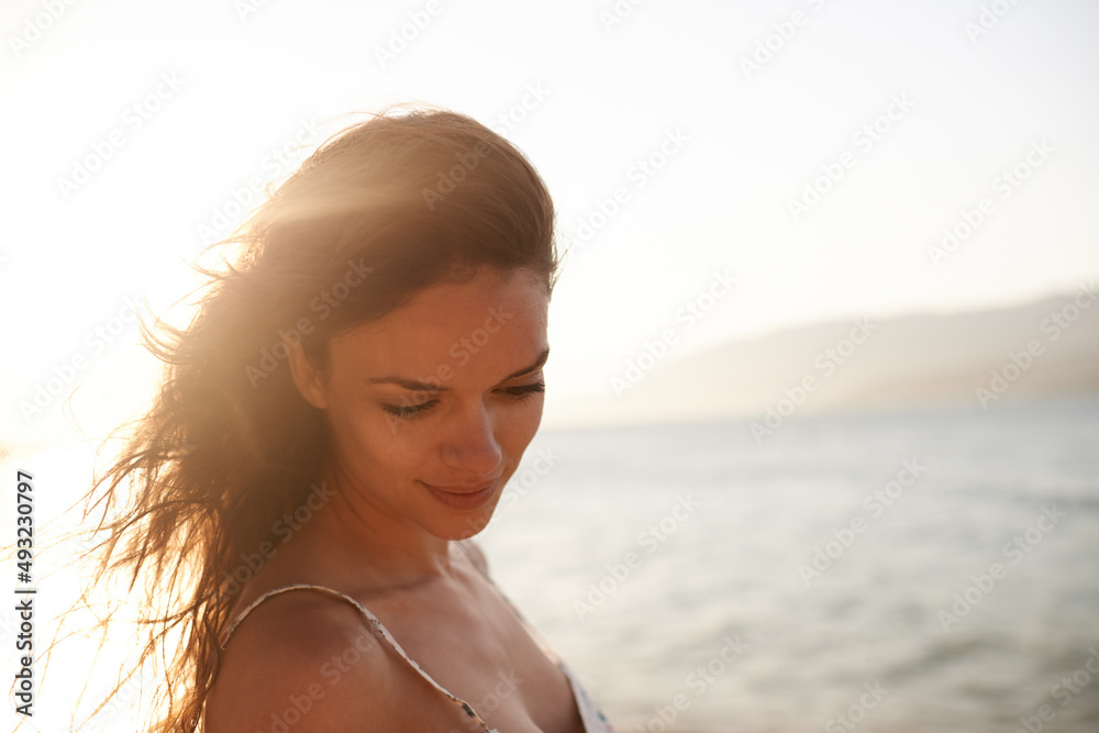 Enjoying the ocean breeze. Cropped shot of a beautiful young woman on the beach.