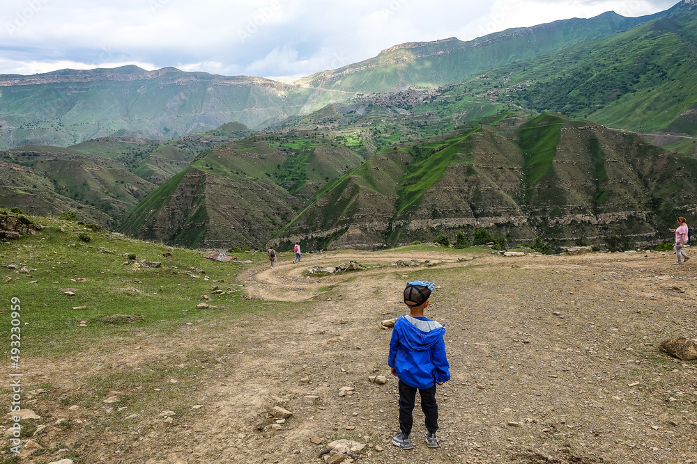 A boy on the background views of the mountains of Dagestan near the village of Gamsutl. Russia June 2021
