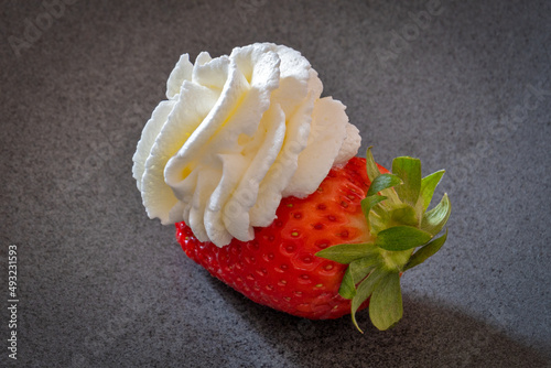 Whole strawberry with whipped cream isolated on gray background photo