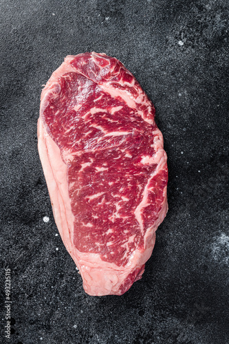 Raw Striploin steak, beef butchery cut. Black background. Top view