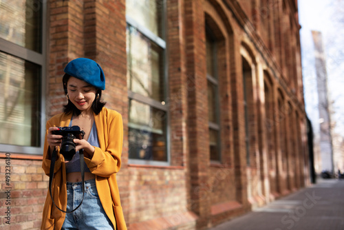 Beautiful Chinese woman with camera. Happy smiling woman taking photos of beautiful location. © Jelena