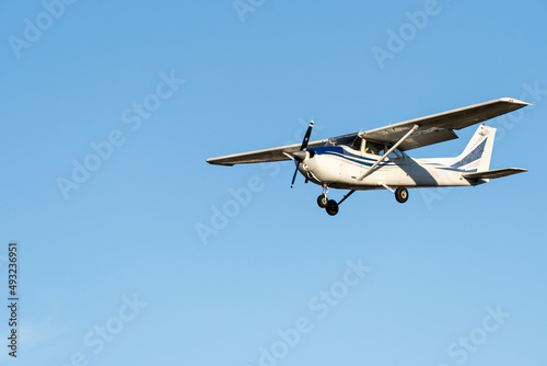 Fototapete Small plane flying with sunset light in a clear sky before landing on Sabadell Airport