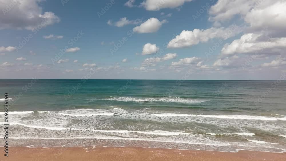 Waves breaking on a clear sandy beach with cloudy blue sky in the background.
Waves breaking on a clear sandy beach with cloudy blue sky in the background.