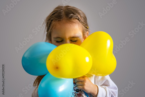 A child holds a poster of no war and balloons, in the yellow-blue colors of Ukraine © Irina Flamingo