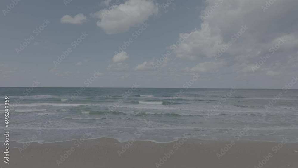 Waves breaking on a clear sandy beach with cloudy blue sky in the background.
Waves breaking on a clear sandy beach with cloudy blue sky in the background.