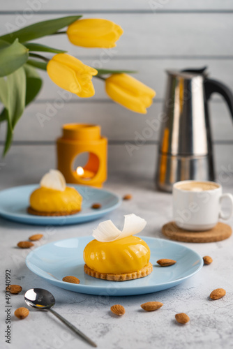 Yellow cupcakes and cup of coffee with yellow tulips on concrete background. Tasty morning dessert