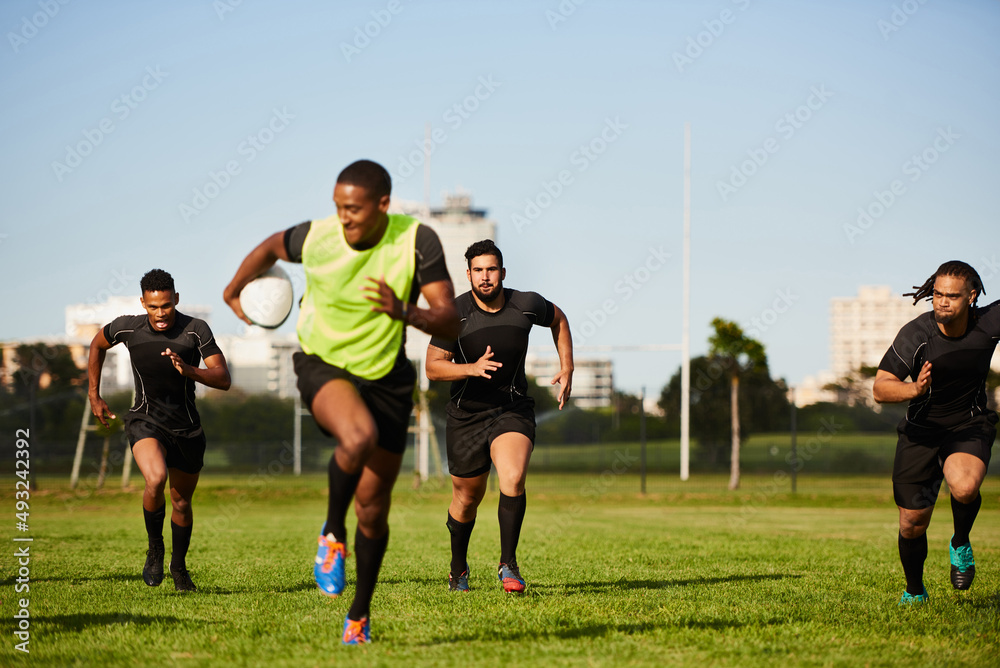 They cant keep up. Full length shot of a diverse group of sportsmen playing a game of rugby during the day.