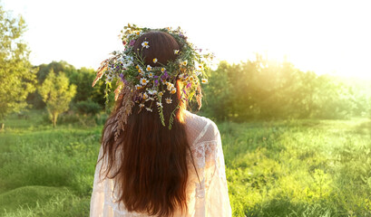 girl in flower wreaths on meadow, sunny green natural background. Floral crown, symbol of summer solstice. Slavic ceremony on Midsummer, wiccan Litha sabbat. pagan holiday Ivan Kupala