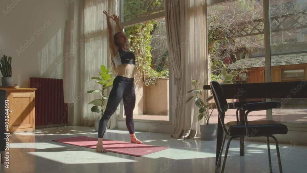 Attractive slim caucasian woman performing Urdhva Dhanurasana asana at home. In sports wear, barefoot, on the matt stretch her body. Beautiful calm interior ambient, good spring or summer weather. 4k Attractive slim caucasian woman performing Urdhva Dhanurasana asana at home. In sports wear, barefoot, on the matt stretch her body. Beautiful calm interior ambient, good spring or summer weather. 4k
