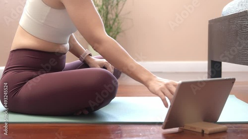 Stylish healthy woman setting her devices, smart watch and tablet computer before practicing yoga asana in bedroom at home. Online class, Technology, Wireless, 5G, Internet, Exercise, Active lifestyle
