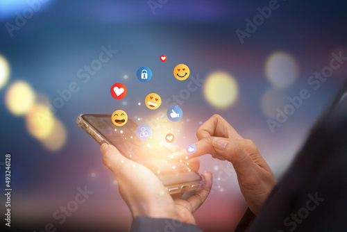 Young man using smartphone sending emojis. Mobile smartphone sending text messages emoji emoticon.