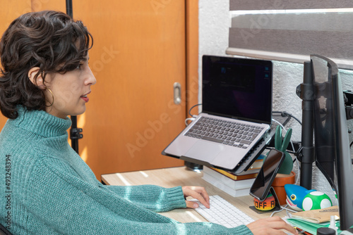 Young Latina woman with a smile works on her computer from home. Home office concept