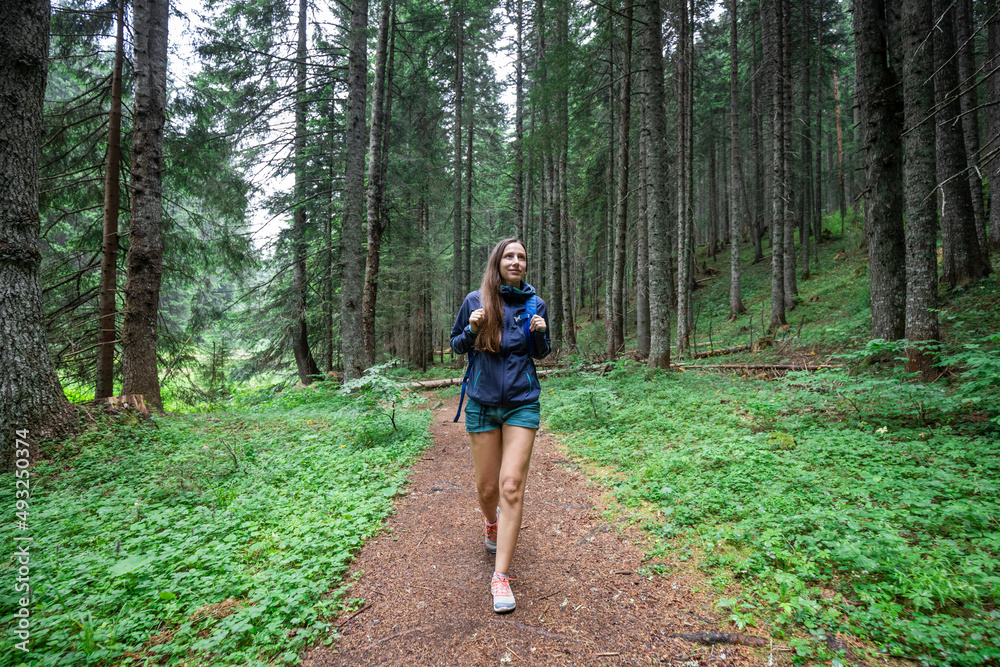 Young smiling woman walking on footpath in the forest Young smiling woman walking on footpath in the forest