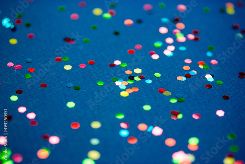 Multicolored confetti on dark blue surface top view. Celebration, party, festive